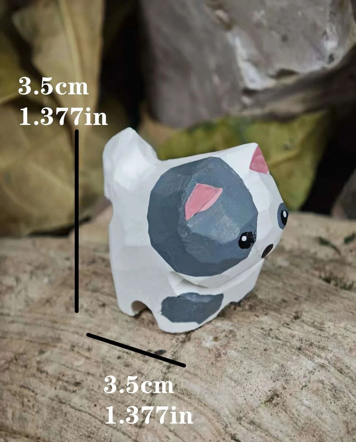 A small painted cat figurine or charm shown on a textured surface with overlaid dimension lines and text reading 3.5 cm / 1.