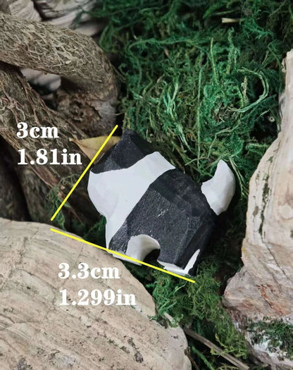 A small black-and-white striped animal toy or figurine placed among rocks and green moss, with yellow measurement lines and text showing dimensions of 3 cm by 3.3 cm.