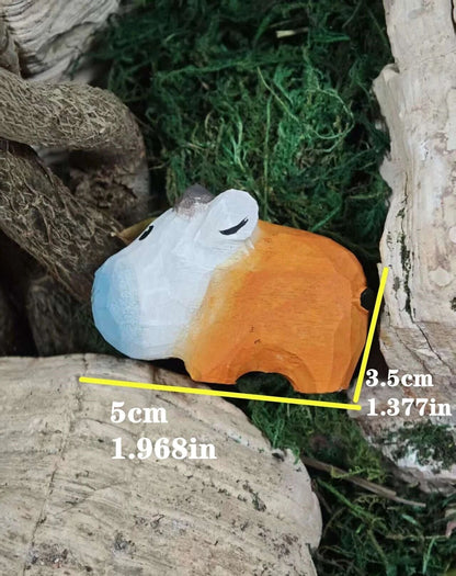 A small carved wooden figurine with a blue, white, and orange gradient finish, resting on natural wood and green moss. Yellow measurement lines and text indicate its dimensions: 5cm in length, 3.