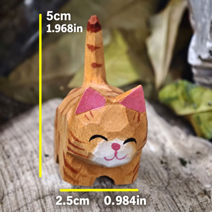 A small carved cat figurine shown with yellow dimension lines and measurements indicating 5 cm height and 2.5 cm width, against a blurred natural background.